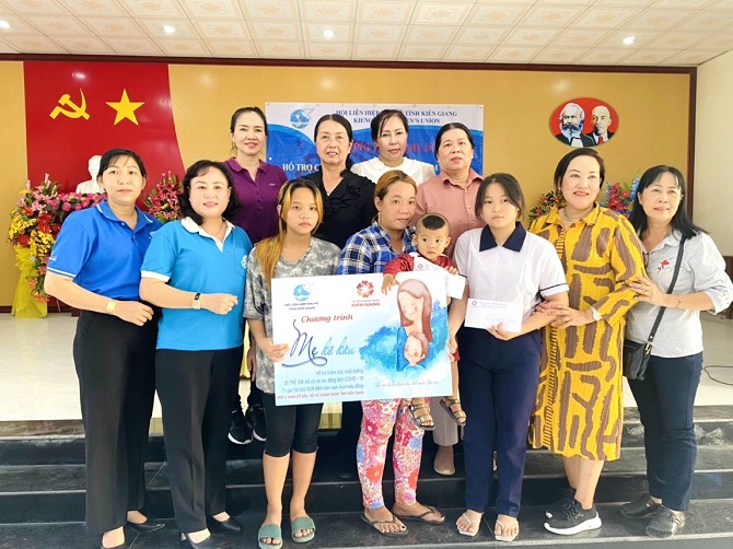 Chủ tịch Hội Nữ doanh nhân tỉnh Kiên Giang Hồ Kim Liên cùng đại diện Hội phụ nữ tỉnh Kiên Giang trao bảng tượng trưng nhận đỡ đầu cho 2 cháu mất cha, mẹ do dịch COVID-19.